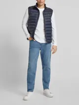 Chaleco acolchado azul marino de nailon reciclado, con cuello alto, cierre de cremallera, bolsillos laterales y logo de Tommy Hilfiger bordado en el pecho.