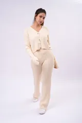Saco de punto acanalado color beige, con escote en V, cierre frontal con botones a contraste y diseño corto.