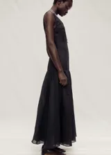 Vestido largo de corte evasé, sin mangas y con cuello redondo. Confeccionado en una mezcla de lino y ramio, presenta un diseño minimalista con falda de vuelo y cierre posterior.