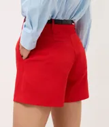 Short sastrero rojo de talle alto, con pinzas delanteras, cierre oculto y bolsillos traseros. Incluye un cinturón delgado de poliuretano.