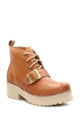 Borcego de cuero color beige con cordones, suela track de goma y detalle de hebilla metálica en el empeine.