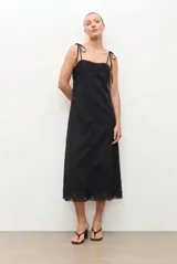 Vestido midi negro con tirantes ajustables mediante lazos, escote recto y detalle de encaje bordado en el pecho y en el ruedo.