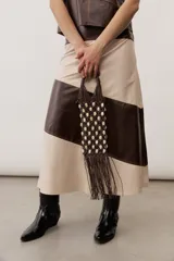 Bolso tipo pouch de diseño artesanal en color marrón, confeccionado con red de macramé decorada con cuentas claras y flecos colgantes en la parte inferior, con asas de mano integradas.