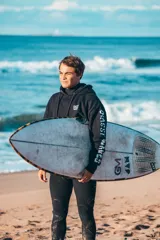 Hoodie negro de corte oversize, con capucha y un gran estampado gráfico en la espalda con marco turquesa y fondo degradado en tonos naranjas y amarillos.
