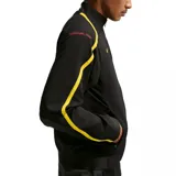 Campera deportiva Nike de cuello alto y cierre frontal completo. Presenta un diseño en color negro con detalles en amarillo en los laterales y hombros. Incluye el logo de Nike bordado en el pecho derecho y un emblema circular con el número 90 en el pecho izquierdo.