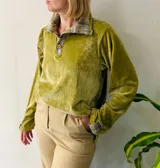 Buzo de plush color verde pistacho con cuello tipo camisa y puños en tela de paño estampada a cuadros. Presenta cierre frontal parcial con botones de madera y mangas largas.