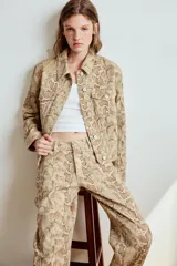 Jeans de tiro bajo con diseño de corte recto y estampado animal print de serpiente, con trabillas, cinco bolsillos y cierre frontal con cremallera y botón metálico.