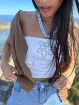 Collar con cadena de macramé en tonos celeste y lila, con dije irregular plateado en forma de flor.