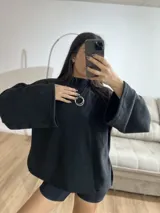 Poleron de cuello alto, color negro, con diseño holgado y mangas amplias.