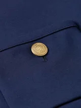 Campera azul marino de tejido de punto con cuello redondo, cierre frontal con botones dorados, mangas largas y dos bolsillos de parche delanteros con detalles de botones dorados.