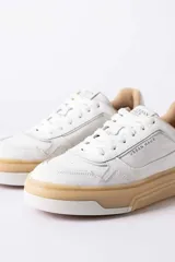 Championes urbanos Urban Haus modelo Alvaro, de cuero blanco con suela de plataforma color caramelo. Presentan cordones al tono y logo de la marca grabado en el lateral y la lengüeta.