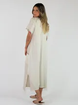Vestido largo azul de corte recto, con escote en V, mangas cortas con flecos y bolsillos laterales.