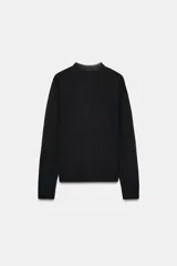 Chaqueta de punto extrafino color negro con cuello redondo y manga larga. Cierre frontal con hilera de botones pequeños.