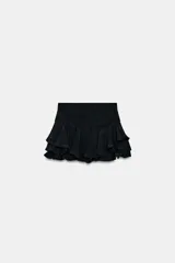 Shorts de tiro medio confeccionado en mezcla de viscosa, con diseño de volantes en el bajo y cierre lateral con cremallera oculta.