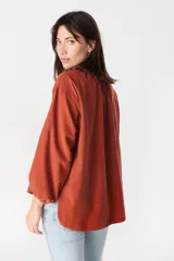 Camisa de corte holgado y diseño minimalista, color crudo, con cuello mao, cierre frontal de botones y mangas largas abullonadas con puños elásticos.