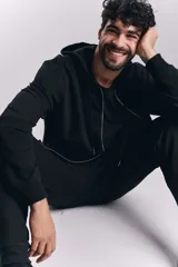 Campera deportiva negra con cierre frontal y capucha con cordones ajustables.