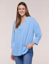 Blusa de silueta holgada confeccionada en tela liviana con diseño de rayas verticales celestes y blancas. Presenta cuello en V profundo con solapa y botones, mangas tres cuartos y ruedo asimétrico con aberturas laterales.