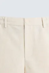 Bermuda de algodón color blanco, de corte relajado, con cintura elástica, bolsillos frontales y bolsillos traseros de plastrón. Cierre frontal con cremallera y botón.