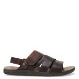 Sandalias de cuero vacuno color marrón habana, con diseño de tiras anchas cruzadas y ajuste mediante velcro en el talón. Presenta detalle de marca grabado en una etiqueta de cuero y suela de goma ergonómica.