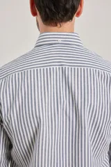 Camisa de manga larga confeccionada en tejido de algodón Oxford, con diseño de rayas verticales en tonos gris y blanco, cuello abotonado y bolsillo frontal.