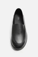 Mocasín negro de piel con construcción desestructurada y suela fina.