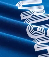 Remera de algodón color azul con cuello redondo y bordes de mangas en color blanco. Presenta la palabra 'URUGUAY' bordada en el centro del pecho con letras blancas y contorno azul.