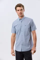Camisa de manga corta de algodón en color celeste con microdiseño geométrico a cuadros, cuello camisero y bolsillo frontal con logo bordado.