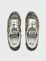 Zapatillas Diesel modelo S-Tracker- D Low, de corte bajo, con capellada de denim desgastado y con bordes deshilachados. Presentan cordones blancos y suela gruesa color crema.