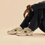 Championes New Balance modelo 740, color blanco con detalles en verde y plateado, confeccionados con capellada de malla transpirable y superposiciones sintéticas. Cuentan con tecnología ABZORB en la entresuela para mayor amortiguación y suela de goma con tracción.
