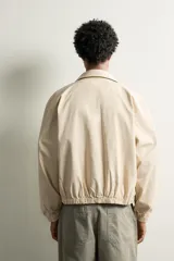 Cazadora cropped fit de algodón color beige, con cuello solapa, manga larga y cierre frontal de cremallera. Cuenta con bolsillos de vivo en la cadera, acabados elásticos y detalle de bordado a tono en el pecho.
