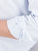 Camisa de hombre Oxford a rayas celestes y blancas, confeccionada en 93% algodón y 7% algodón reciclado. Corte regular fit, cuello button-down, cierre con botones, manga larga con puño simple y logo bordado en el pecho.