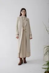Tapado largo de paño en color beige, con solapas clásicas, cierre frontal de dos botones y corte recto estructurado.