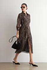 Vestido midi camisero de manga larga con estampado animal print en tonos marrón y negro, cuello camisero, cierre frontal con botones y lazo ajustable para la cintura.