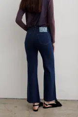 Jean de denim azul de tiro medio, con corte flare y costuras frontales destacadas.