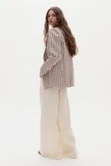 Blazer cruzado de lino con diseño de rayas verticales burdeos sobre fondo beige, solapas de muesca, bolsillos delanteros de parche y doble botonadura con botones claros.