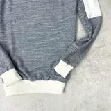 Buzo gris con mangas ranglan blancas y logo bordado en el pecho.