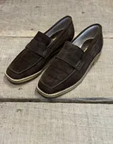 Mocasín de gamuza color marrón chocolate con textura grabada tipo cocodrilo, diseño de punta cuadrada y suela de goma clara.