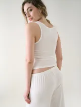 Musculosa básica entallada de tela pointelle color blanco, con escote redondo y detalle de ondas en los bordes.