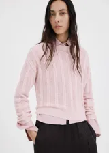 Chaleco de tejido de punto calado, color rosado, con diseño recto y cuello redondo.