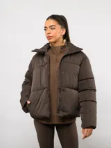 Campera puffer corta Umbro de color negro, con cuello alto, cierre frontal y bolsillos laterales. Presenta un diseño acolchado y logo de la marca bordado en el pecho.