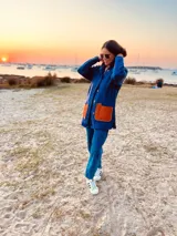 Saco de lana azul con bolsillos de cuero color naranja, botones al frente y tajos a los costados.