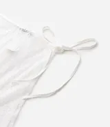 Pañuelo de cintura femenino confeccionado en encaje blanco con diseño floral, con amarre lateral y terminación irregular.