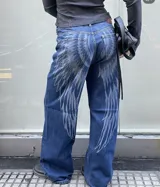 Jean de corte recto y tiro medio, color azul lavado con estampado de alas en tono más claro que recorre la parte trasera y los laterales de las piernas.