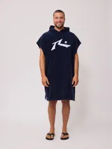 Poncho de toalla con capucha en color azul marino, confeccionado en 100% algodón. Presenta un bordado blanco del logo de Rusty en el pecho.