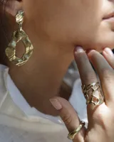 Par de aros colgantes de bronce y alpaca color plateado, con forma orgánica irregular y textura martillada. Cierre con perno y mariposa de plata 925.