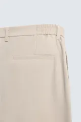 Pantalón de corte regular fit, color negro, confeccionado en tejido elástico. Presenta cintura elástica, cierre frontal con cremallera y botón, bolsillos laterales y bolsillos traseros de vivo.