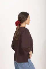 Blusa marrón de lino y viscosa con escote en V y cuello adornado con volados plisados, mangas tres cuartos y corte recto.