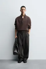 Jersey de punto de corte regular, color gris oscuro, con cuello subido y cierre frontal de cremallera. Presenta mangas largas y acabados en rib en puños y ruedo.