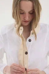 Chaqueta de lino marrón con cuello mao en contraste negro, cierre frontal con botones y hombreras.