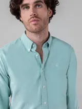 Camisa celeste de corte clásico, con cuello abotonado, manga larga y logo bordado en el pecho.